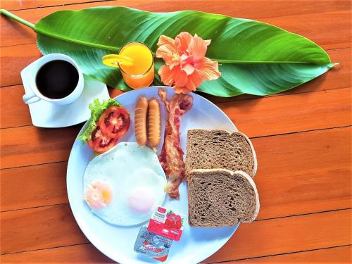 a plate of breakfast food with eggs sausage and a cup of coffee at Koh Jum Coral Bay Resort in Ko Jum