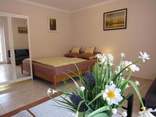 - un salon avec un lit et un vase de fleurs dans l'établissement Bella Studio Apartment, à Hajdúszoboszló