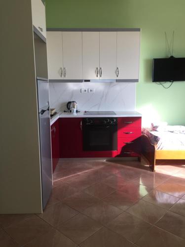a kitchen with red and white cabinets and a stove at Mana Apartments in Ksamil