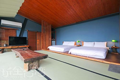 a bedroom with two beds and a tv and a bench at Yue Lake Backpackers in Yuchi