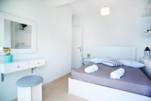 a white bedroom with a bed with two pillows at MOUSELIS APARTMENTS in Kalymnos