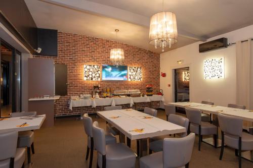 a restaurant with white tables and chairs and a brick wall at Hôtel Le Verger De Bischwiller in Bischwiller