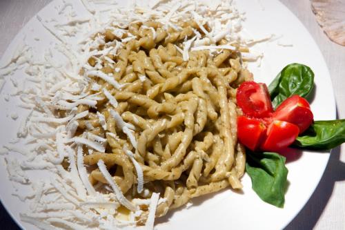 a white plate of pasta with tomatoes and lettuce at Mira Spiaggia in San Vito lo Capo