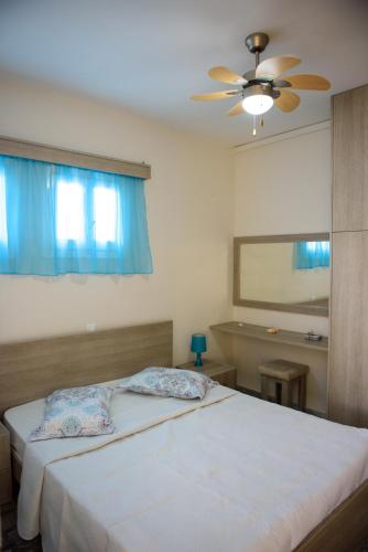 a bedroom with a bed with a ceiling fan at MOUSELIS APARTMENTS in Kalymnos