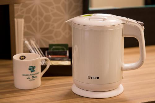 a white electric kettle on a table next to a cup at Hotel Monterey Le Frere Osaka in Osaka