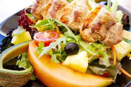 a plate of food with a salad and fruit at Hôtel Le Verger De Bischwiller in Bischwiller