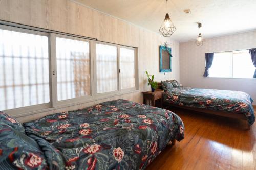 um quarto com uma cama, um sofá e janelas em 沖縄古民家お宿ななつぼし Okinawa Traditional House Nanatsuboshi em Naha