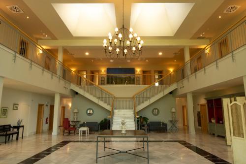 un gran vestíbulo con una escalera y una lámpara de araña en Hotel Villa Marcilla, en Marcilla