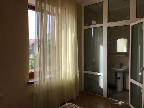 a bathroom with a sink and a window with curtains at Veranda Guest House in Chornomorsk