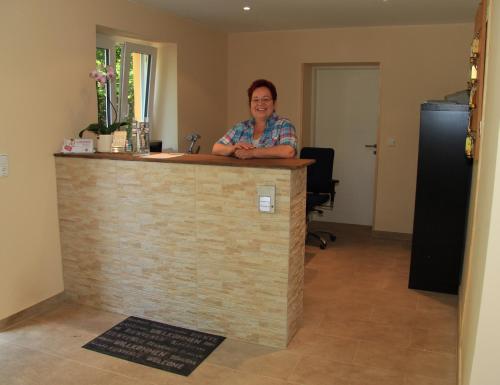 a woman standing behind a counter in a room at Waldhotel Albachmühle mit Albacher Stuben in Wasserliesch