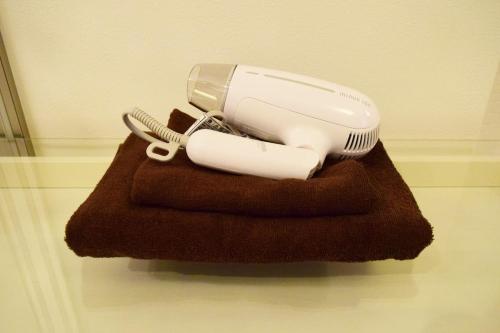 a hair dryer sitting on top of a brown towel at Three Tokyo 102 in Tokyo