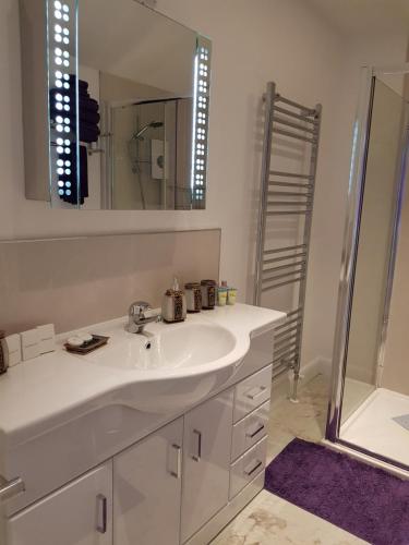 a white bathroom with a sink and a mirror at Delny Muir House in Invergordon
