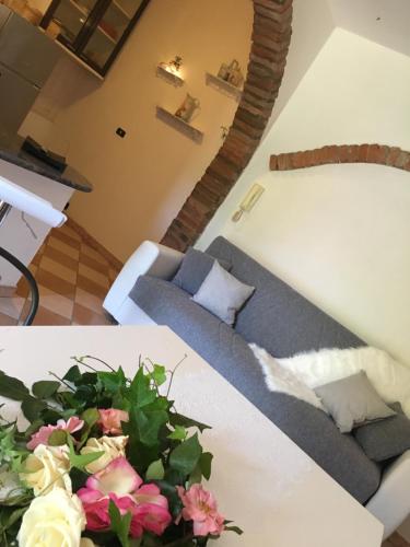 a living room with a couch and a table with flowers at Rossella alla Villarella dei Tulipani in Asti