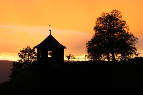 a clock tower with a cross on top of it at sunset at Ferienwohnung mit Panoramablick in Viktorsberg