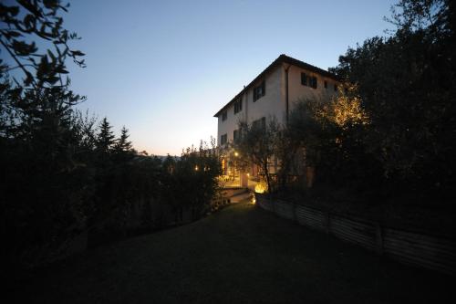 a building at dusk with the sun setting behind it at B&B Le Dimore Mezza Costa in San Casciano in Val di Pesa