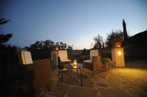 a patio with chairs and a table and lights at B&B Le Dimore Mezza Costa in San Casciano in Val di Pesa