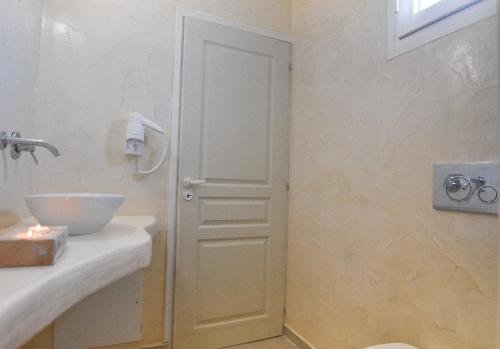 a bathroom with a white door next to a sink at Sea Wave Villa in Perissa