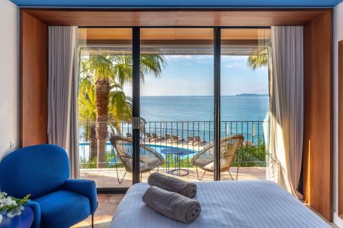 een slaapkamer met een bed en uitzicht op de oceaan bij Hôtel Le Bailli De Suffren in Rayol-Canadel-sur-Mer