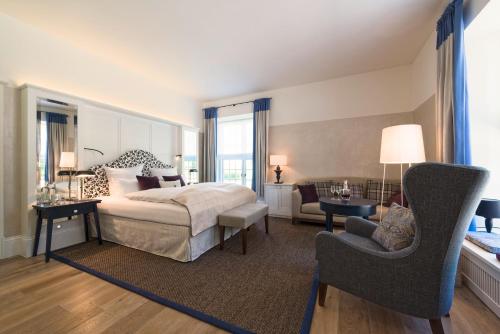 a bedroom with a bed and a chair and a couch at Weissenhaus Private Nature Luxury Resort in Weißenhaus