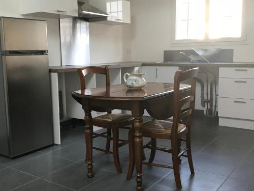 une cuisine avec une table en bois, des chaises et un vase. dans l'établissement Appartement récent, proche centre ancien, à Bayonne