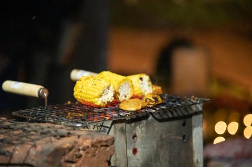 a grill with corn and two hamburgers on it at Campistaan Karjat in Karjat