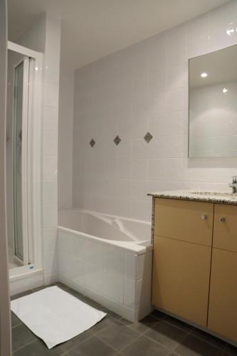 une salle de bain blanche avec une baignoire et un miroir dans l'établissement Residence Reine Marine, à Saint-Malo
