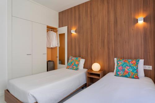 two beds in a small room with wooden walls at Next Inn in Portimão