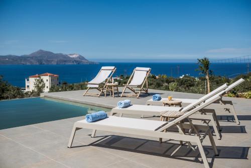 a group of chairs and tables next to a swimming pool at NiMar Villas in Plaka