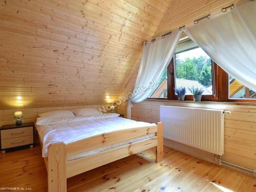 a bedroom with a bed in a wooden house at Bajkowe Domki in Pobierowo