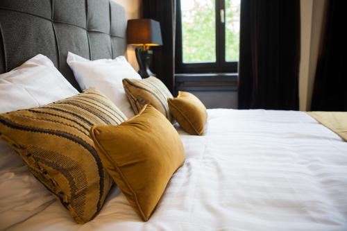 a bed with yellow pillows and white sheets and a window at B in Antwerp in Antwerp