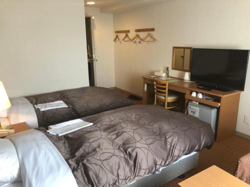 a hotel room with a bed and a desk with a television at Chitose Airport Hotel in Chitose