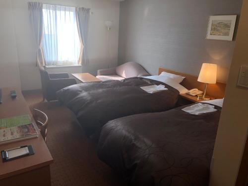 a hotel room with two beds and a window at Chitose Airport Hotel in Chitose