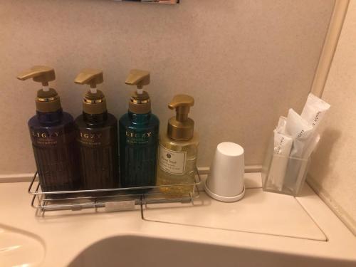 a rack with four bottles of soap and a sink at Chitose Airport Hotel in Chitose