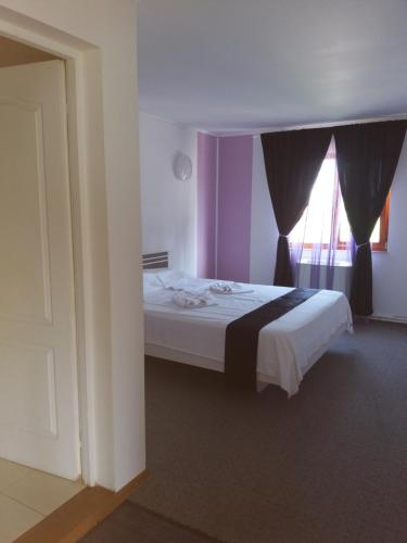 a bedroom with a white bed with a window at Hotel Hobby in Hunedoara