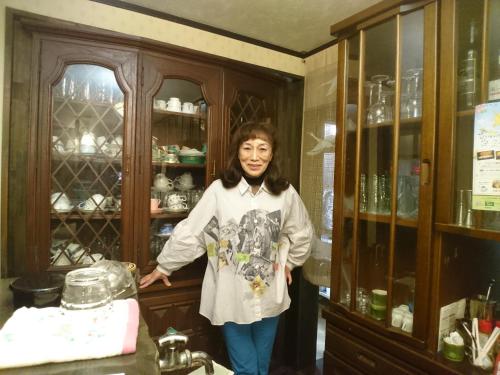 a woman standing in a kitchen next to a cabinet at Live Cafe Hisui no Umi in Itoigawa