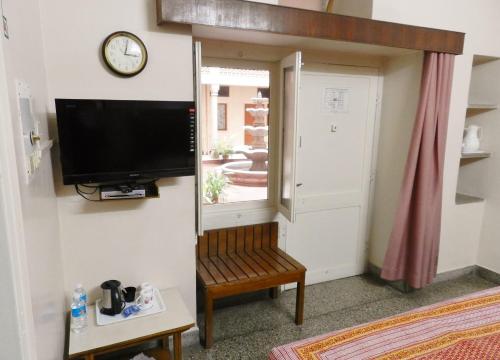 a room with a tv and a chair and a window at Hotel Arya Niwas in Jaipur