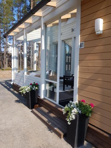eine abgeschirmte Veranda eines Hauses mit zwei Topfpflanzen in der Unterkunft Rantahiekka B1 in Kalajoki