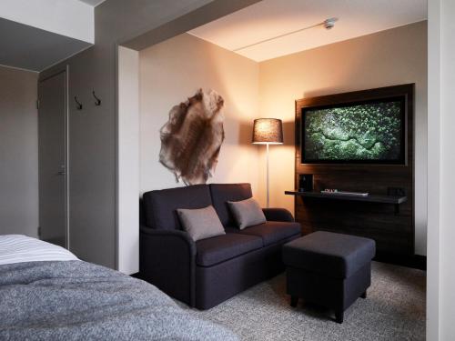 a hotel room with a couch and a tv at Lapland Hotels Kuopio in Kuopio