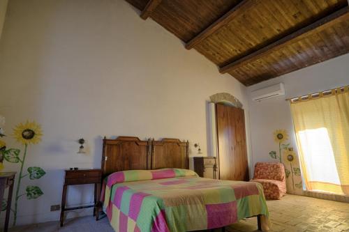 a bedroom with a bed and a chair and a window at Agriturismo Giardino di Iti in Rossano
