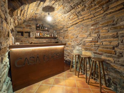 a bar in a stone walled room with stools at Apartamento Casa Dueso in El Pueyo de Araguás