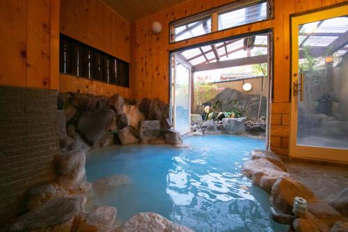 uma grande piscina de água num quarto com pedras em Oyado Ichizen em Yufu