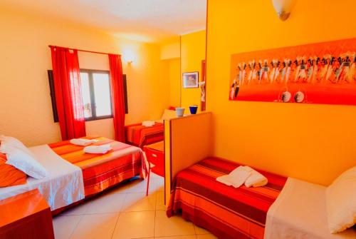 two beds in a room with yellow walls at Villa Sunset B&B/Apartments in Fontane Bianche
