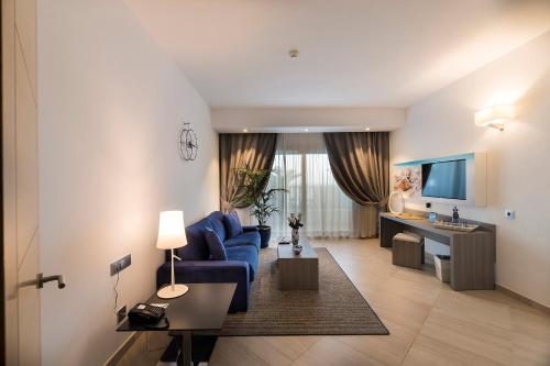 a living room with a blue couch and a kitchen at Royal Palm Resort & Spa - Adults Only in Playa Jandia