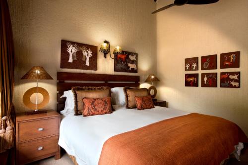 a bedroom with a large bed and pictures on the wall at Kruger Park Lodge in Hazyview