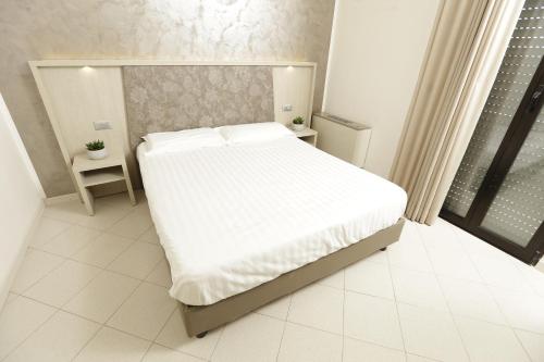 1 dormitorio con 1 cama grande con sábanas blancas en Residenza Sol Holiday, en Rímini