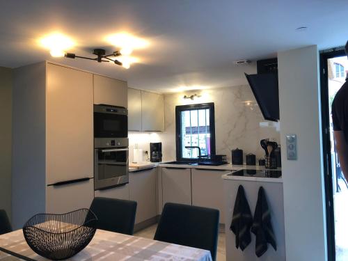 une cuisine avec des armoires blanches et une table avec des chaises dans l'établissement Les Oceanes, à Gruissan