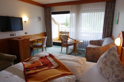 ein Hotelzimmer mit einem Bett, einem Schreibtisch und einem Tisch in der Unterkunft Hotel Hirsch mit Café Klösterle in Enzklösterle