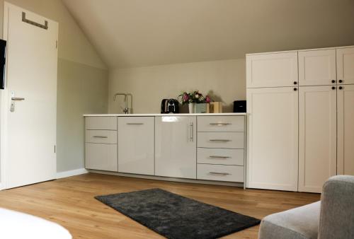 a white kitchen with white cabinets and a rug at Stadt Apartments Burg Fehmarn in Burg auf Fehmarn