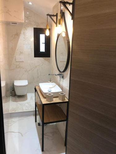 ein Badezimmer mit einem Waschbecken, einem Spiegel und einem WC in der Unterkunft Les Oceanes in Gruissan