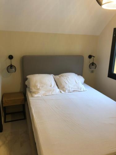 ein Bett mit weißer Bettwäsche und Kissen in einem Schlafzimmer in der Unterkunft Les Oceanes in Gruissan